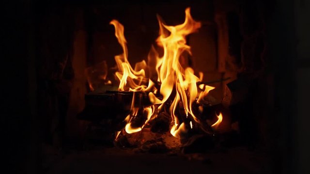 Close-up shot of warm cozy burning fire in a brick fireplace.  Slow motion. Shoot in 100 fps and slowed to 50 fps