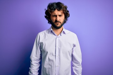 Young handsome business man with beard wearing shirt standing over purple background depressed and worry for distress, crying angry and afraid. Sad expression.