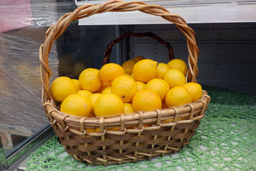 ripe juicy yellow lemons in a wicker basket on a shelf in the store