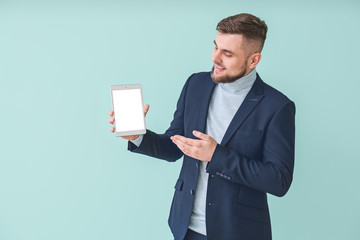 Young businessman with tablet computer on color background