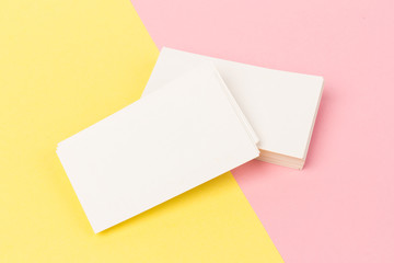 white blank business cards on pink and yellow background in close-up