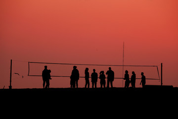 Fototapeta na wymiar silhouettes of people playing volleyball in the evening on the beach at sunset