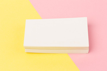 white blank business cards on pink and yellow background in close-up