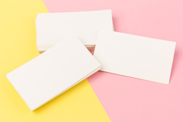 white blank business cards on pink and yellow background in close-up