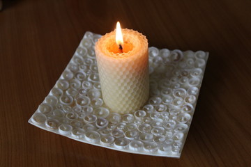 Burning white candle on the plate made of seashells