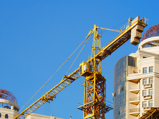 Industrial crane near building against blue sky. Construction site.