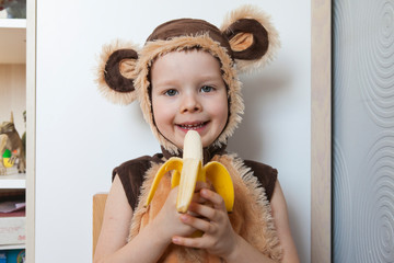 Image of cute toddler wearing a monkey costume, eating a banana