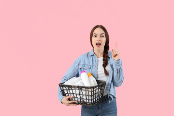 Beautiful young woman with laundry and detergents on color background