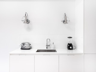 New stylish bright kitchen with white cabinets. Spacious modern interior with wooden floor, white table, industrial chairs and big ceiling window.