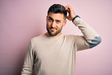 Young handsome man wearing casual sweater standing over isolated pink background confuse and wonder about question. Uncertain with doubt, thinking with hand on head. Pensive concept. - obrazy, fototapety, plakaty