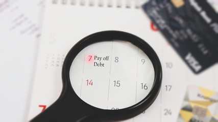 Close up of magnifying glass Pay off debt  money as managing credit card debt and The words Payment for written to remind  an important appointment.