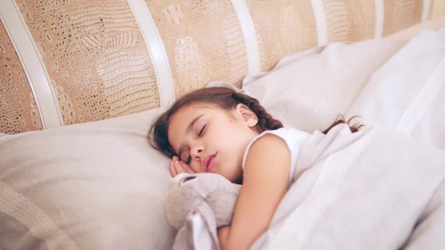 Little girl lies on the bed, sleeps early in the morning