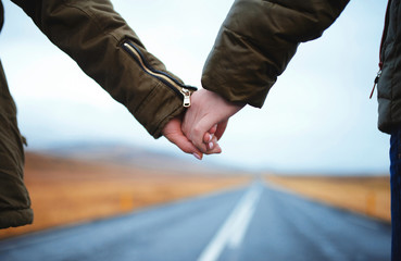 couple holding hands on road