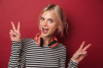 Image of nice excited woman with headphones gesturing peace sign