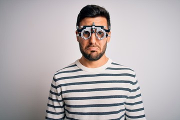 Young handsome man with beard wearing optometry glasses over isolated white background depressed and worry for distress, crying angry and afraid. Sad expression.