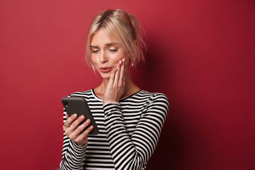Fototapeta premium Image of nice happy woman in striped sweatshirt typing on cellphone
