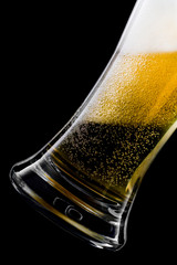 Beer from a bottle pours into a glass on a dark background