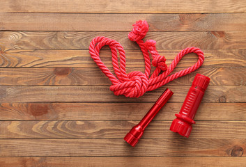 Modern flashlights with rope on wooden background