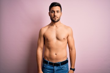 Young handsome strong man with beard shirtless standing over isolated pink background Relaxed with serious expression on face. Simple and natural looking at the camera.