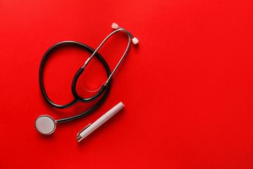 Modern flashlight with stethoscope on color background