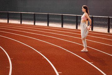 Fitness sporty woman runner stretching legs before run on the stadium