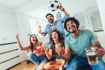 Very excited friends having fun by watching football match and eating at home, indoors. Friendship, leasure, rest, home party concept