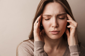 Photo of young beautiful woman with headache rubbing her temples