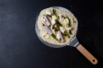 selbstgemachte Pizza mit Mascarpone, Mozzarella, Sauce hollandaise, grünem Spargel, Truthanschinken auf einer Seite, Studio