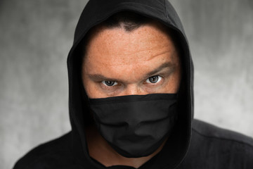 A man in a hood and a white medical mask