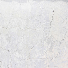the white wall of an old house with beautiful cracks from time. white paint and whitewash on the wall. the background is white with soft blue and yellow. white old wall background