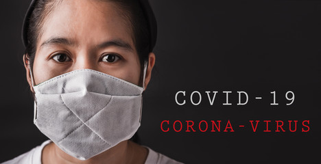 Closeup Asian young woman wearing protective face mask with fear in the eye, prevent germs or disease hygiene prevention COVID-19 virus or coronavirus protection concept, dark on black background