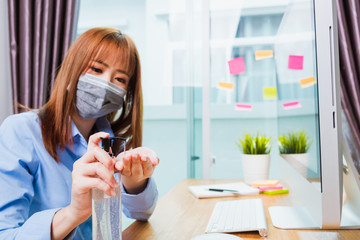 Fototapeta premium Asian young business woman wearing face mask protective working from home office with laptop computer he quarantines disease coronavirus or COVID-19 and cleaning hands with sanitizer alcohol gel pump