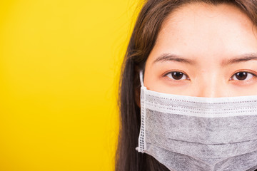 Closeup Asian young teen woman wearing face mask protective against coronavirus, COVID-19 virus or filter dust pm2.5 and air pollution she looking camera studio shot isolated yellow background