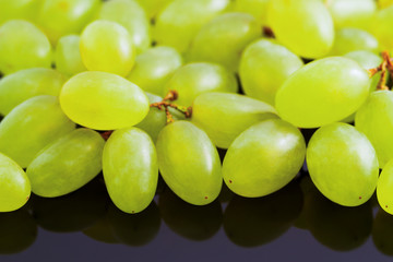 Grape berries close-up on a black mirror background