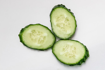 green cucumber cut into pieces on a white background macro shot