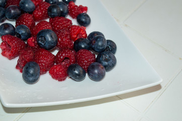 Blueberries And Raspberries Isolated on a white plate. White background.