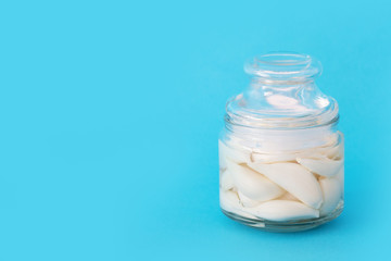 fermented garlic in a closed transparent jar on a blue table.