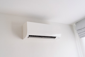 Air conditioner on white concrete wall in area of bedroom.