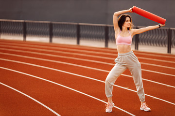 Young beautiful woman doing exercises outdoor, training process.