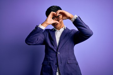 Young handsome business man wearing jacket and glasses over isolated purple background Doing heart shape with hand and fingers smiling looking through sign