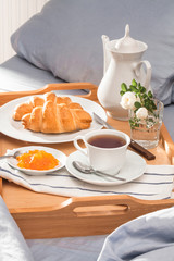 Breakfast in bed, a tray of tea, flowers, croissants, jam. Honeymoon. Early morning at the hotel.