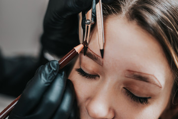 Cosmetologist measures the proportions of the eyebrows with the ruler. Micropigmentation work flow...
