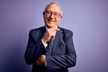 Grey haired senior business man wearing glasses and elegant suit and tie over purple background...