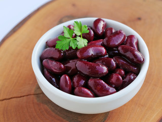 Dark red kidney beans in white bowl over wooden board