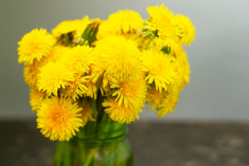 Bouquet of yellow flowers in a glass green jar.