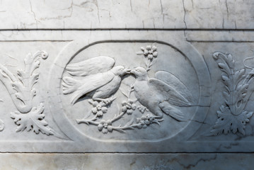 Black and white photo showing illustration of two pigeons kissing carved on a marble wall