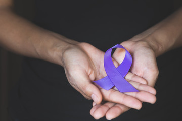 Woman Hand Holding Purple Ribbon, Domestic Violence Awareness Month (October) concept with deep...
