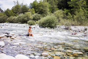 Little child in the middle of a wild river