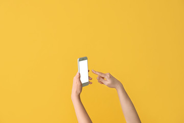 Female hands with mobile phone on color background