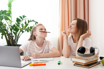 Mother and daughter having fun during remote learning at home, homeschooling education, making...